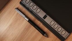 Digital stylus and power strip arranged on wooden surface next to dark background.