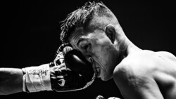 Boxer receiving a punch to the face during a match against black background.