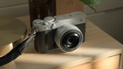 Fujifilm Instax rangefinder camera with black leather grip displayed on wooden surface in daylight.