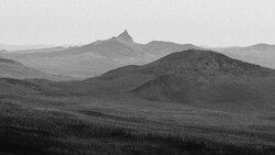 Layered mountain ranges receding into atmospheric haze, with a prominent peak centered in the middle distance.