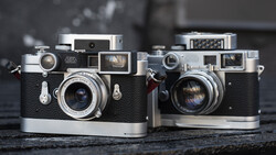 Two vintage rangefinder cameras with black leather bodies and chrome accents displayed side by side.