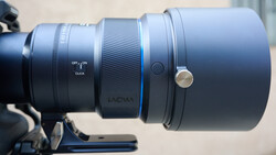 Close-up of a telephoto lens mounted on a camera, showing focus ring, depth of field markings, and manual focus controls.