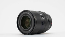 Black telephoto zoom lens with visible focus ring and distance scale on neutral background.