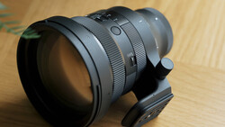 Fast telephoto lens with focus ring and depth-of-field markings mounted on wooden surface.