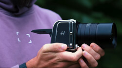 Photographer holding a medium format film camera with telephoto lens attachment.