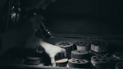 Film reels and storage containers arranged on a surface in dramatic low-key lighting.
