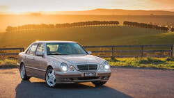 Silver sedan parked on a rural road at golden hour, with rolling hills and tree lines in the background.