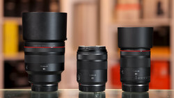 Three Canon RF-mount lenses of varying focal lengths arranged side by side on a reflective surface.