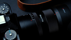 Black camera lens with f/8 aperture marking and manual focus ring, positioned next to vintage camera body with exposure dials.
