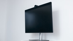 Modern monitor with black display on silver pedestal stand against white wall.