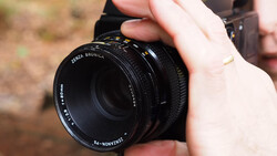 Hands holding a Zenza Bronica medium format camera lens in outdoor daylight.