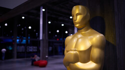 Golden Oscar statue in profile against blurred evening venue lighting.
