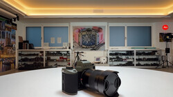 Leica rangefinder camera with telephoto lens displayed on white surface in photography studio.