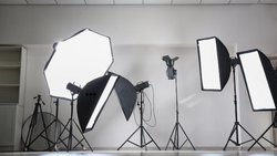 Professional studio lighting setup with softboxes, reflectors, and tripod stands arranged in a white studio space.