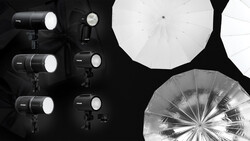 Professional studio lighting setup with multiple LED panel lights and large diffusion umbrellas arranged on black background.