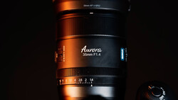 Aurora 35mm F1.4 lens with focus and aperture rings visible against dark background with dramatic orange and blue lighting.