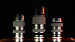 Three telephoto lenses arranged side by side against black background with warm rim lighting.