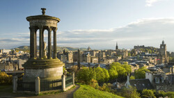 Stone monument with columned rotunda overlooking a historic cityscape with church spires and buildings.