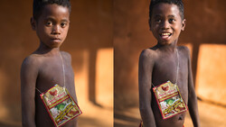 Young child holding a packaged food item, smiling at camera in warm indoor lighting.