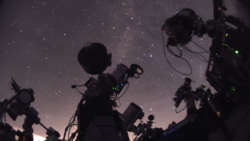 Film and television camera equipment silhouetted against a starry night sky.