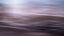 Blurred landscape with horizontal motion blur across layered terrain in purple and brown tones.