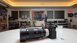 Sony FE 70-200mm f/2.8 GM telephoto lens displayed on studio workbench with camera gear visible in background shelving.