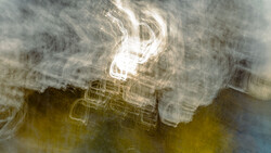 Abstract motion blur with bright white light core surrounded by yellow and gray layered streaks.