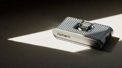 Hohem smartphone gimbal stabilizer on white surface with dramatic diagonal sunlight creating sharp shadow contrast.