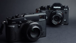 Three rangefinder-style digital cameras arranged on a gray surface with selective focus on the foreground model.