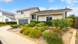 Contemporary two-story residential home with cream-colored siding, glass garage door, and drought-resistant landscaping.