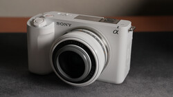 White Sony Alpha mirrorless camera with attached prime lens, shown from a three-quarter front view.