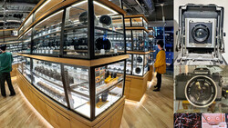 Illuminated display cases in a camera equipment showroom with vintage and modern cameras on shelves.