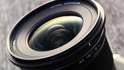 Close-up of a wide-angle lens showing the front element and autofocus markings with textured surface details.