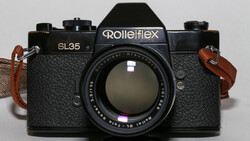 Rollei SL35 film camera with Carl Zeiss lens and brown leather neck straps on gray background.