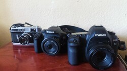 Three Canon cameras arranged in chronological order on a wooden surface, ranging from vintage rangefinder to modern DSLR.