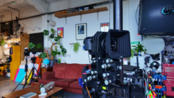 Large format camera mounted on tripod in creative studio workspace.