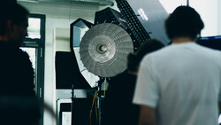 Studio lighting setup with a large circular reflector and key light mounted on stands during a production shoot.