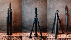 Four telescoping camera tripods displayed in different extended positions against a textured backdrop.
