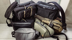 Collection of black and tan camera bags and cases arranged on a white surface.