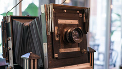 Vintage large-format view camera with bellows and lens, displayed in natural window light.