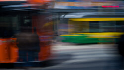 Multiple buses in motion blur during evening hours with warm and cool lighting.