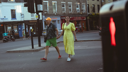 Two joggers crossing a city street at a red traffic light in bright daylight.
