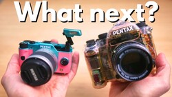Two colorful Pentax toy cameras held in hands against a beige background.