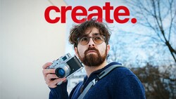 Photographer holding a rangefinder camera with a red 'create.' text overlay above.