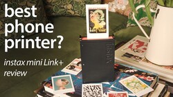 Instax Mini Link+ printer surrounded by instant photo prints on a patterned surface with floral decorations.