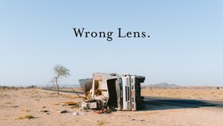 Overturned vehicle lying on its side in an arid desert landscape with sparse vegetation.