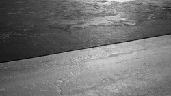 Dark water meeting a concrete edge in sharp contrast, minimal geometric composition.