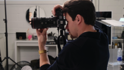 Cameraman operating cinema camera on tripod in studio setting