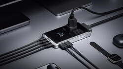 Smartphone with USB charging hub connected to multiple cables on minimalist desktop