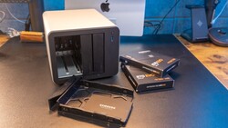 Samsung SSD storage drives and black card reader displayed on desk with Mac computer in background.
